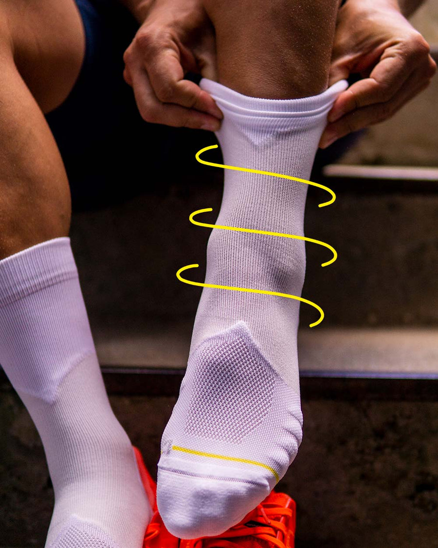 Erklärung der Rollo Socks Funktion anhand eines All White Sockens der auf einer Treppe angezogen wird